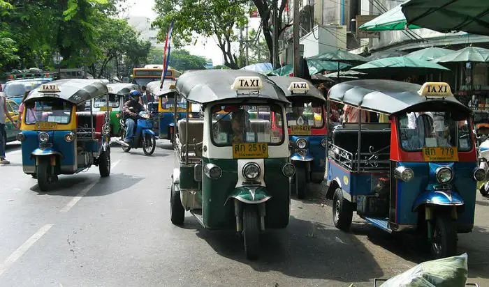 Uma frota de tuk-tuks aguardando passageiros.